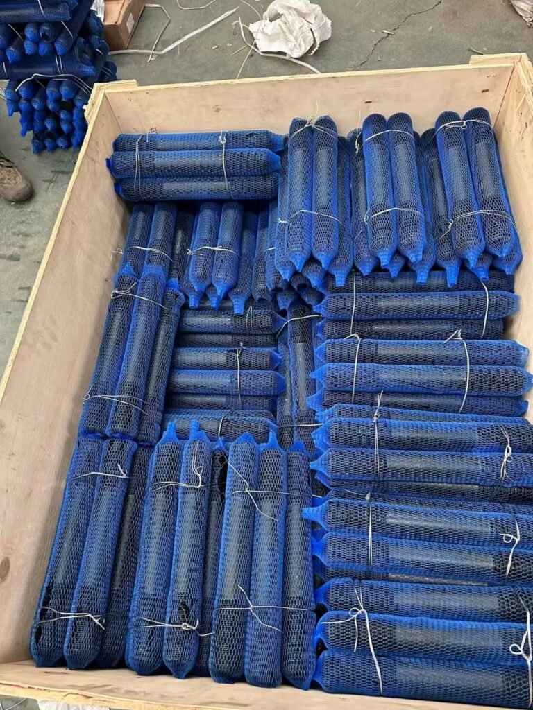 Long threaded components protected with blue mesh sleeves in a wooden export crate